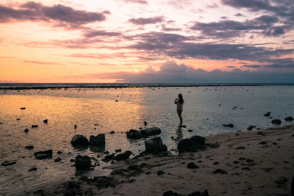 sunset on west coast of gili trawangan with woman standing on beach