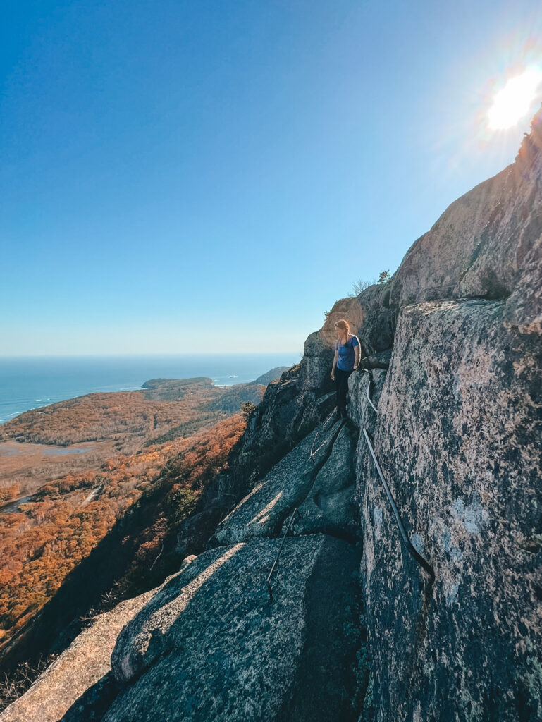hiker on ledge overlooking frenchman bay in acadia
