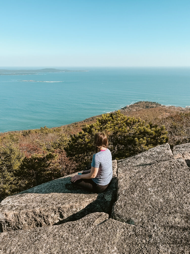 woman hiker on top of champlain mountain overlooking frenchman bay acadia