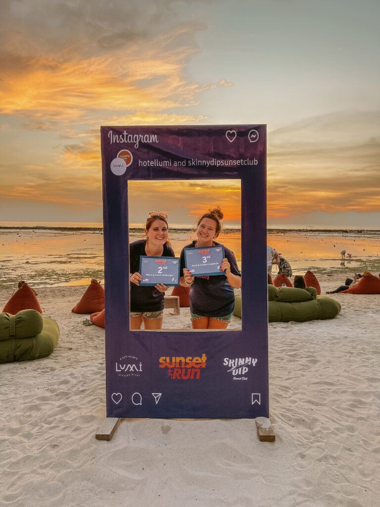 two girls at the lumi sunset run gili trawangan beach with awards for trash pick up competition 