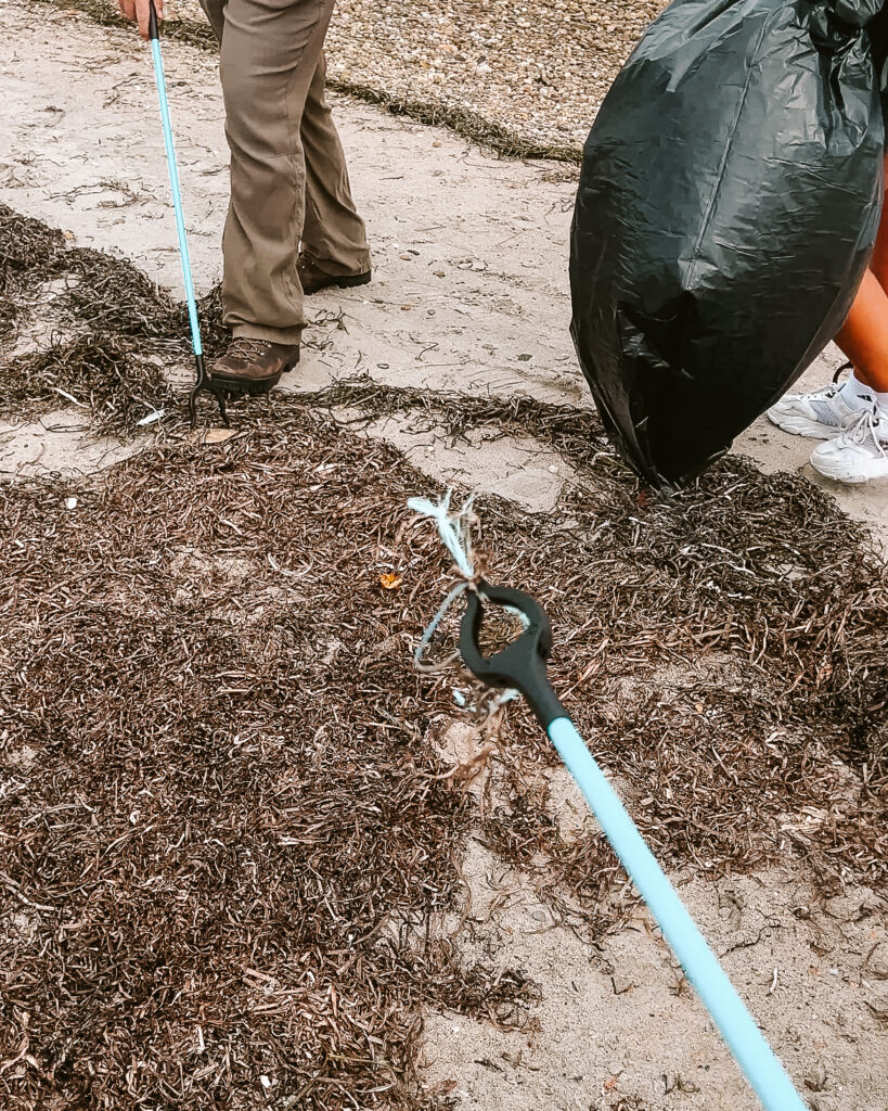 trash picker with piece of beach trash and garbage bag