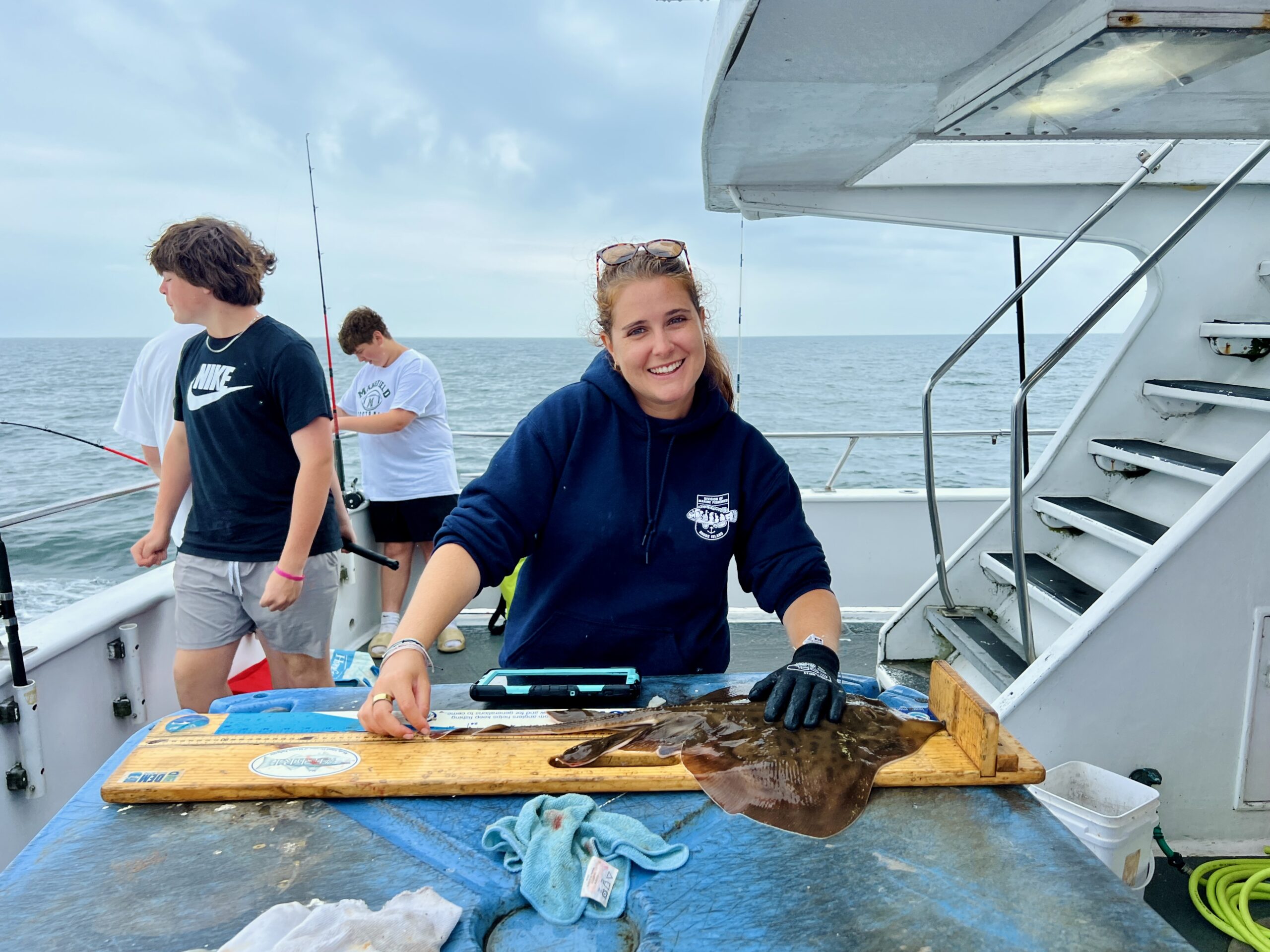 woman field fisheries scientist on boat measuring a ray